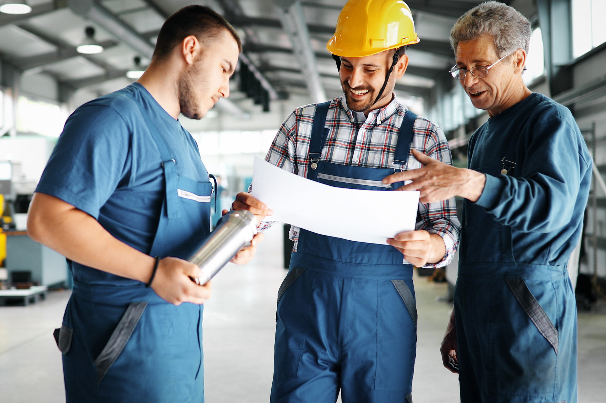 Team of smiling engineers reviewing documents in a factory